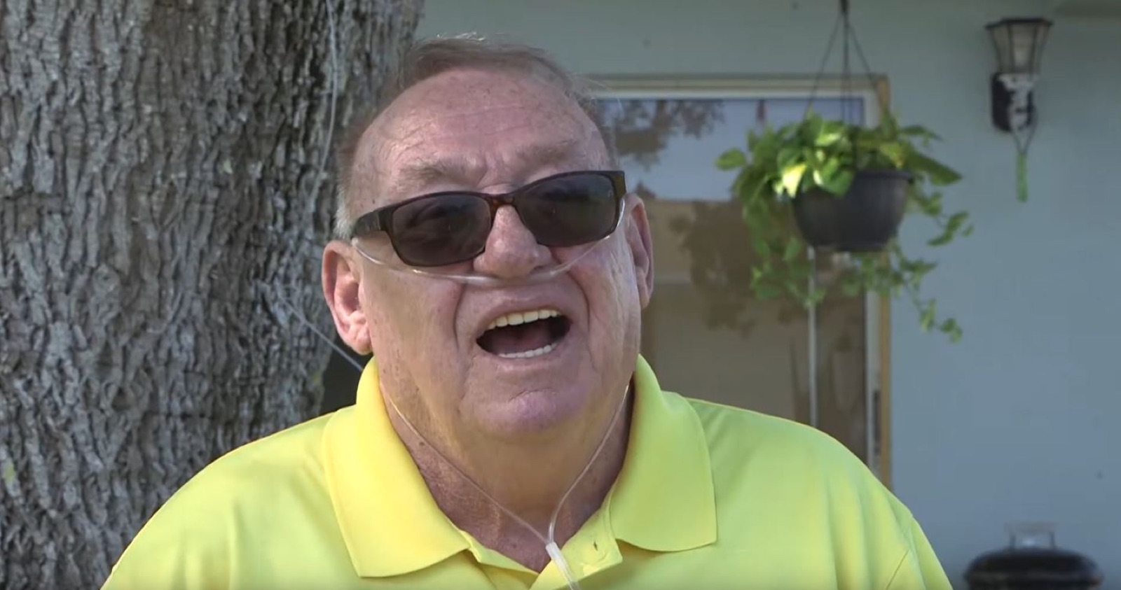 Still from Sunset Eddy: an older man in sunglasses and a yellow shirt, laughing on his porch.